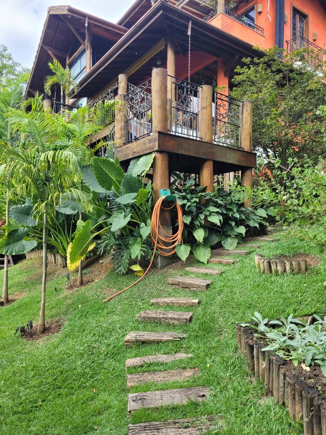 Gramado em declive com caminho de dormentes até a varanda de madeira