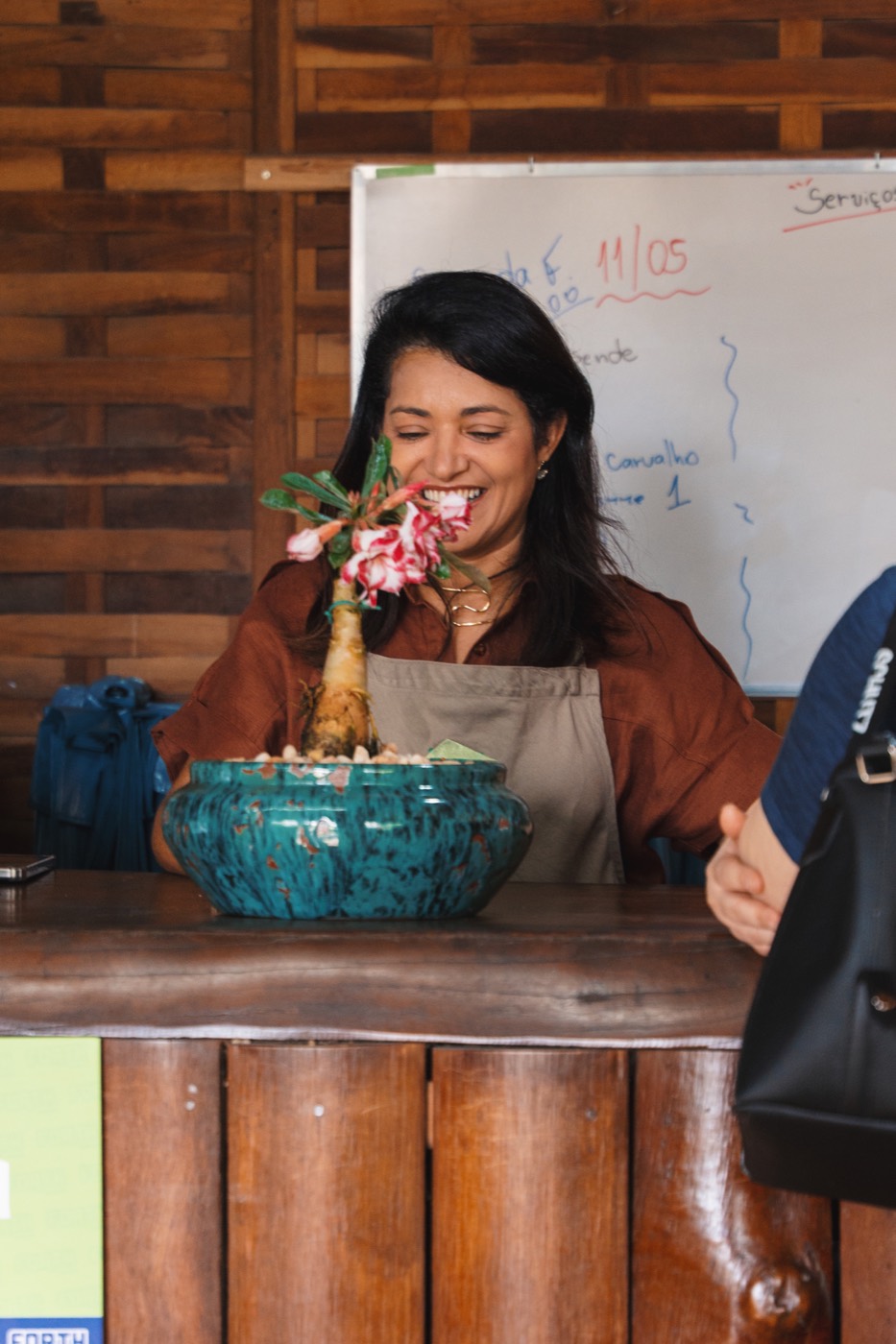 Atendente da Casa e Flor sentindo o perfume de uma flor no balcão da loja